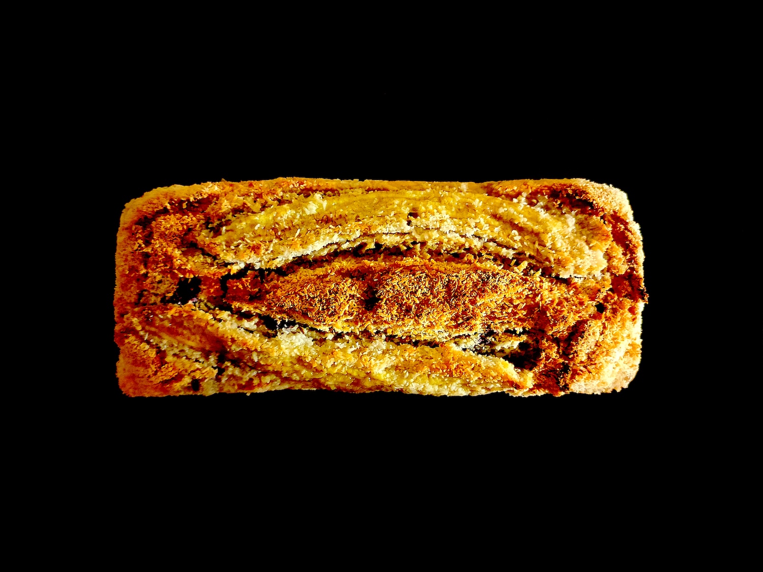 Le dessus du cake ne laisse aucun doute sur 2 composantes de l’association des goûts de ce banana bread. La banane décorative caramélisée et la noix de coco râpée bien toastée vendent la mèche.